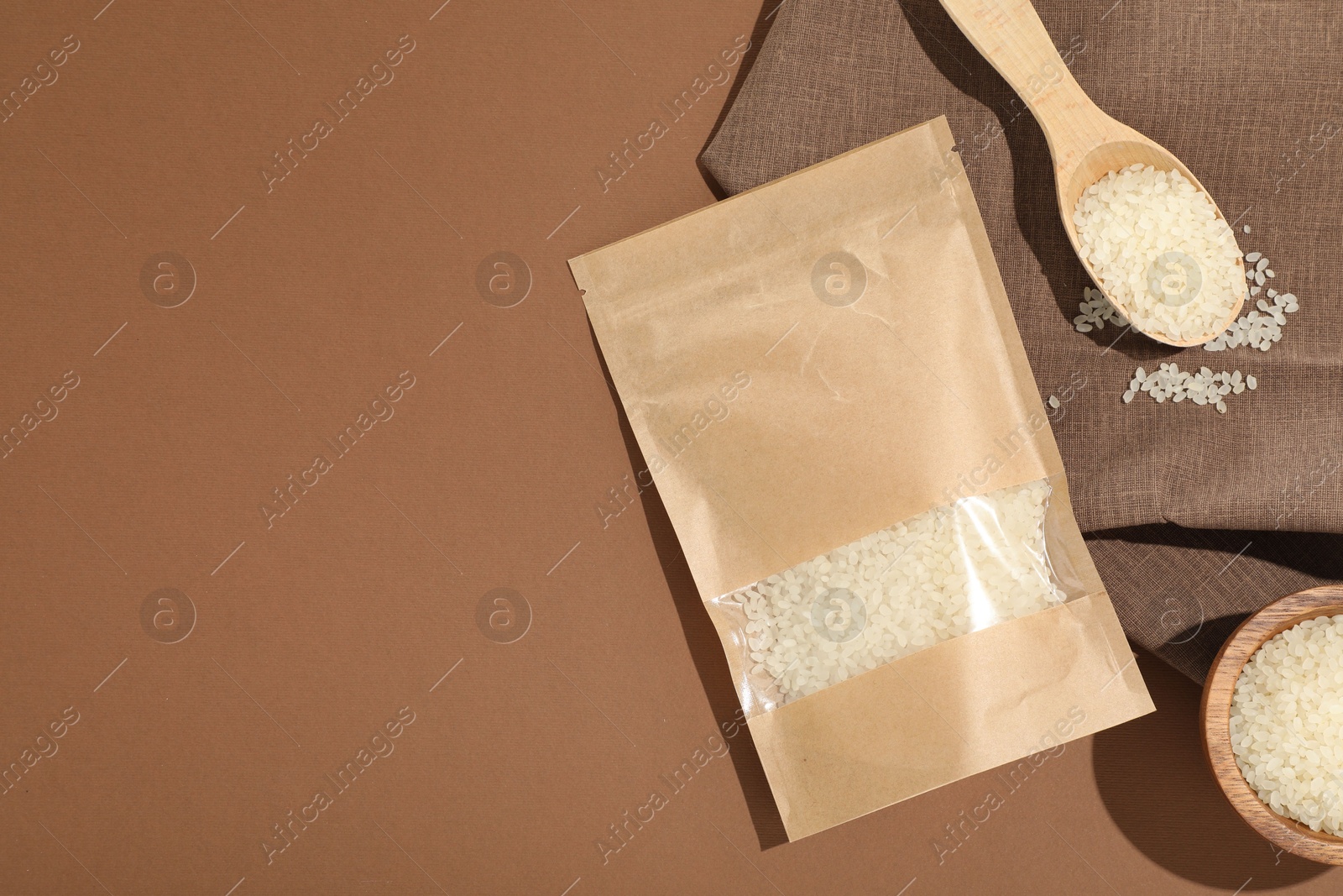 Zipper stand-up pouch and white rice on brown background, flat lay. Mockup for design Photo of Zipper stand-up pouch and white rice on brown background, flat lay. Mockup for design