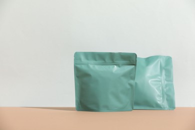 Photo of Zipper stand-up pouches on beige table against light grey background, mockup for design