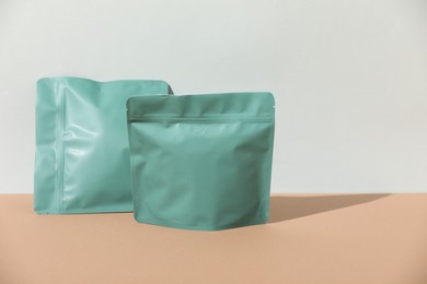 Photo of Zipper stand-up pouches on beige table against light grey background, mockup for design