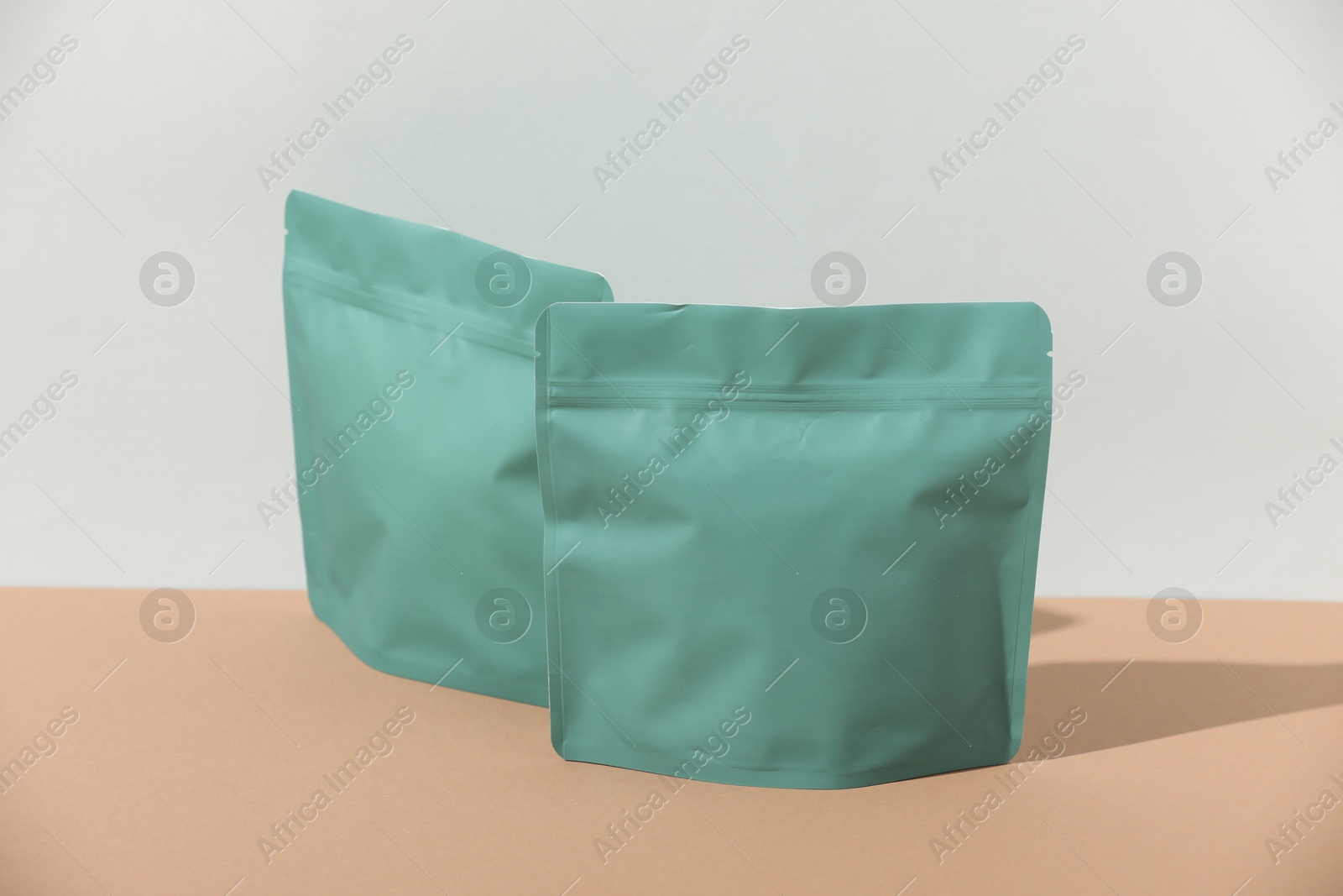 Zipper stand-up pouches on beige table against light grey background, mockup for design Photo of Zipper stand-up pouches on beige table against light grey background, mockup for design