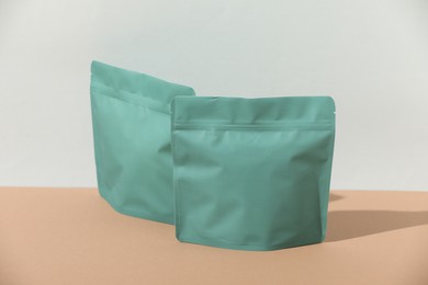 Photo of Zipper stand-up pouches on beige table against light grey background, mockup for design