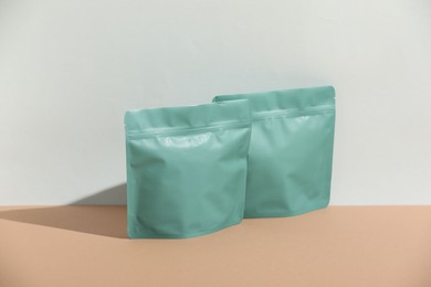 Photo of Zipper stand-up pouches on beige table against light grey background, mockup for design