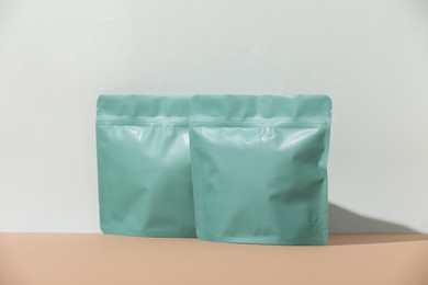 Photo of Zipper stand-up pouches on beige table against light grey background, mockup for design