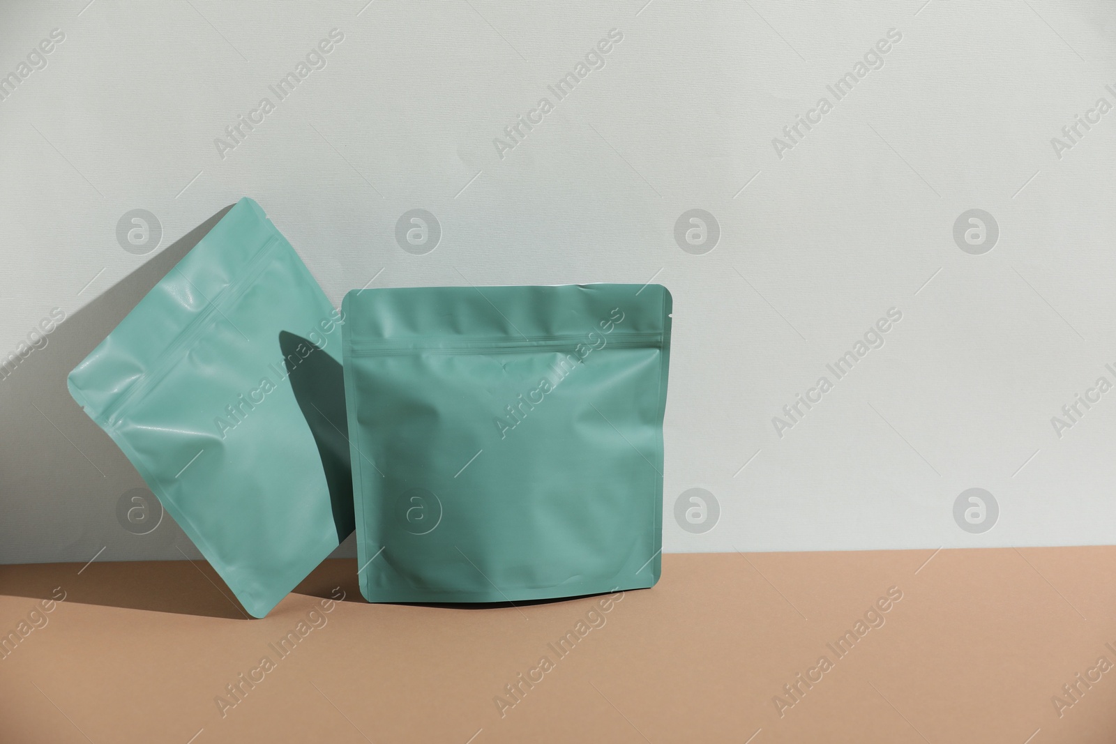 Zipper stand-up pouches on beige table against light grey background, mockup for design Photo of Zipper stand-up pouches on beige table against light grey background, mockup for design