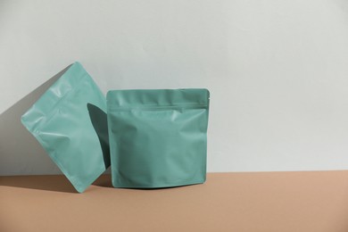 Photo of Zipper stand-up pouches on beige table against light grey background, mockup for design