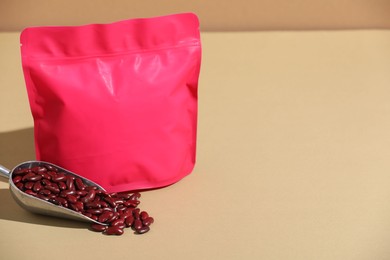 Photo of Zipper stand-up pouch and dry kidney beans on beige background, mockup for design