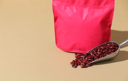 Photo of Zipper stand-up pouch and dry kidney beans on beige background, closeup. Mockup for design