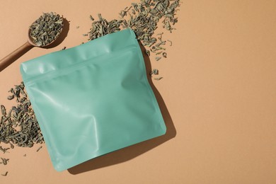 Photo of Zipper stand-up pouch and dry leaves on beige background, flat lay. Mockup for design