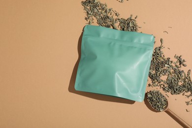 Photo of Zipper stand-up pouch and dry leaves on beige background, flat lay. Mockup for design