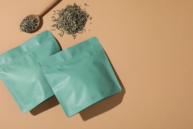 Photo of Zipper stand-up pouches and dry leaves on beige background, flat lay. Mockup for design