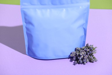 Photo of Zipper stand-up pouch and lavender flowers on violet background, closeup. Mockup for design