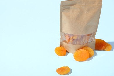 Photo of Zipper stand-up pouch with dried apricots on light blue background, closeup. Mockup for design
