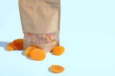 Photo of Zipper stand-up pouch with dried apricots on light blue background, closeup. Mockup for design