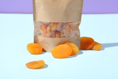 Photo of Zipper stand-up pouch with dried apricots on light blue background, closeup. Mockup for design