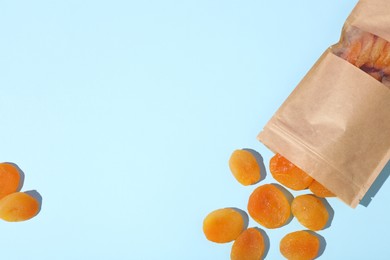 Photo of Zipper stand-up pouch with dried apricots on light blue background, flat lay. Mockup for design