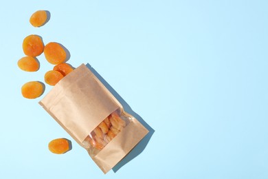 Photo of Zipper stand-up pouch with dried apricots on light blue background, flat lay. Mockup for design