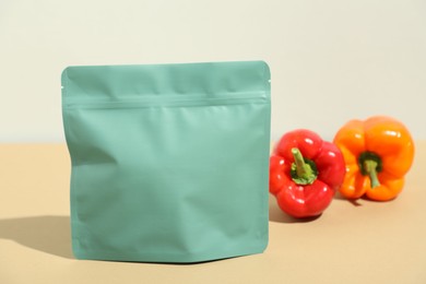 Photo of Zipper stand-up pouch and bell peppers on beige table, closeup. Mockup for design