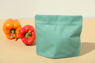 Photo of Zipper stand-up pouch and bell peppers on beige table, closeup. Mockup for design