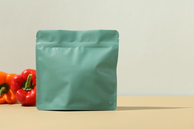 Photo of Zipper stand-up pouch and bell peppers on beige table against grey background. Mockup for design