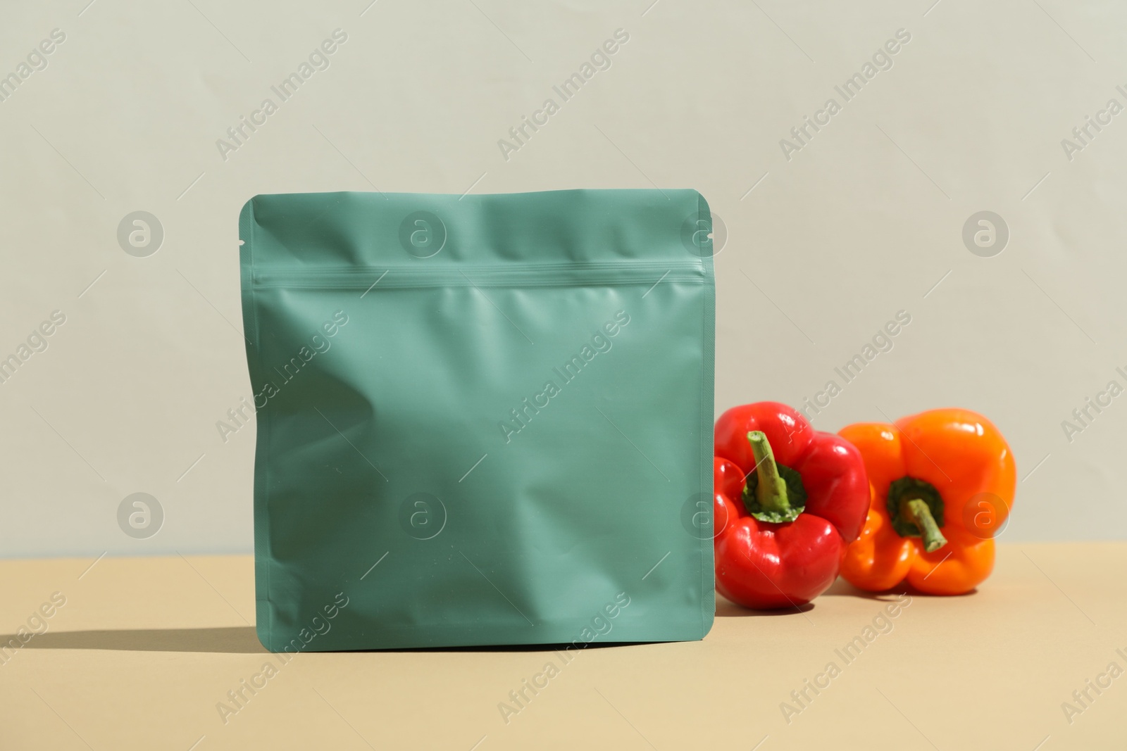 Zipper stand-up pouch and bell peppers on beige table against grey background. Mockup for design Photo of Zipper stand-up pouch and bell peppers on beige table against grey background. Mockup for design