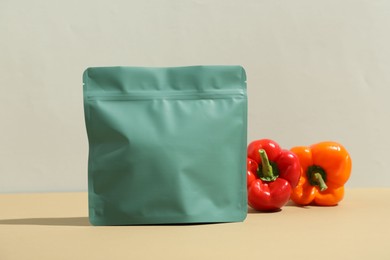 Photo of Zipper stand-up pouch and bell peppers on beige table against grey background. Mockup for design
