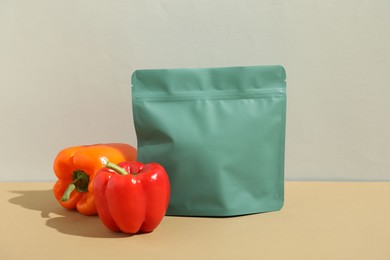 Photo of Zipper stand-up pouch and bell peppers on beige table against grey background. Mockup for design