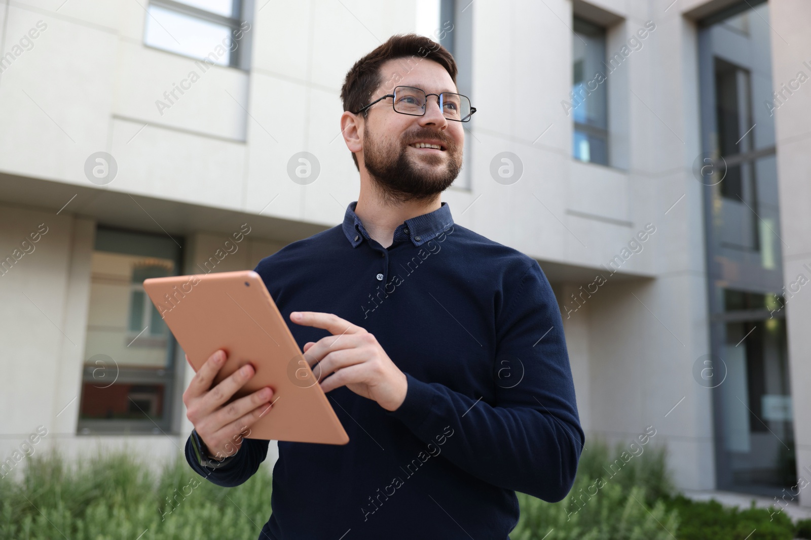 Photo of Happy businessman with tablet near office building