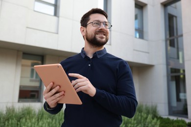 Photo of Happy businessman with tablet near office building