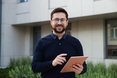 Photo of Happy businessman with tablet near office building