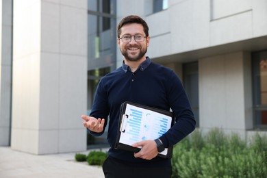 Photo of Happy businessman with clipboard near office building