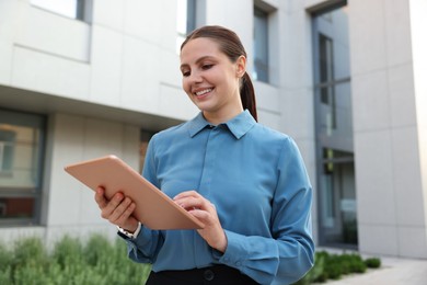 Photo of Happy businesswoman with tablet near office building