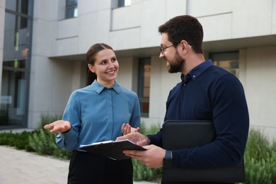 Photo of Happy coworkers discussing something near office building