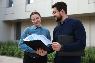Photo of Happy coworkers discussing something near office building