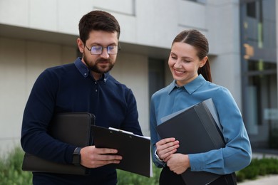 Photo of Happy coworkers discussing something near office building