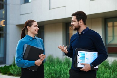 Photo of Happy coworkers discussing something near office building