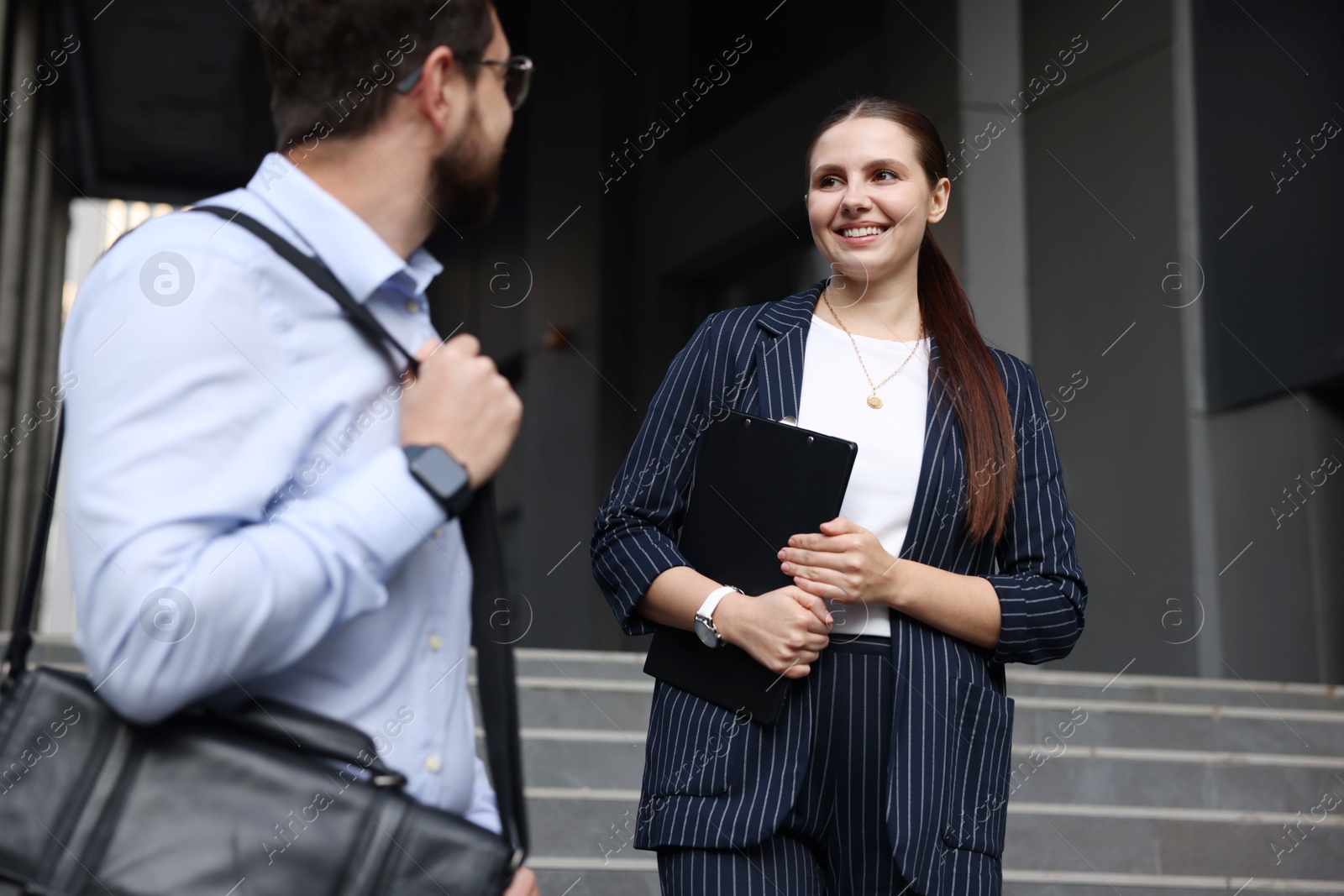 Photo of Happy coworkers discussing something near office building