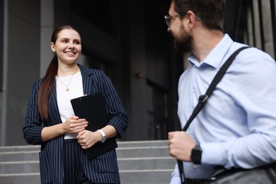 Photo of Happy coworkers discussing something near office building