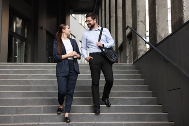 Photo of Happy coworkers on stairs near office building