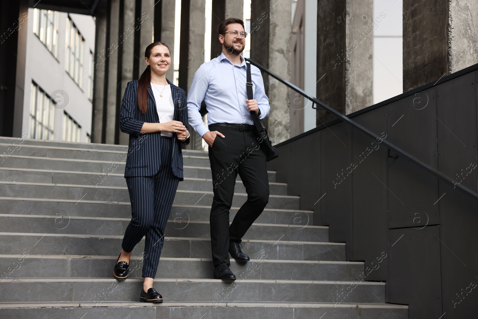 Happy coworkers on stairs near office building Photo of Happy coworkers on stairs near office building