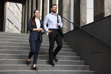 Photo of Happy coworkers on stairs near office building