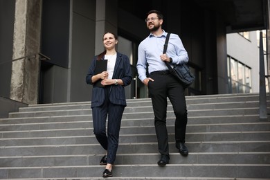 Photo of Happy coworkers on stairs near office building