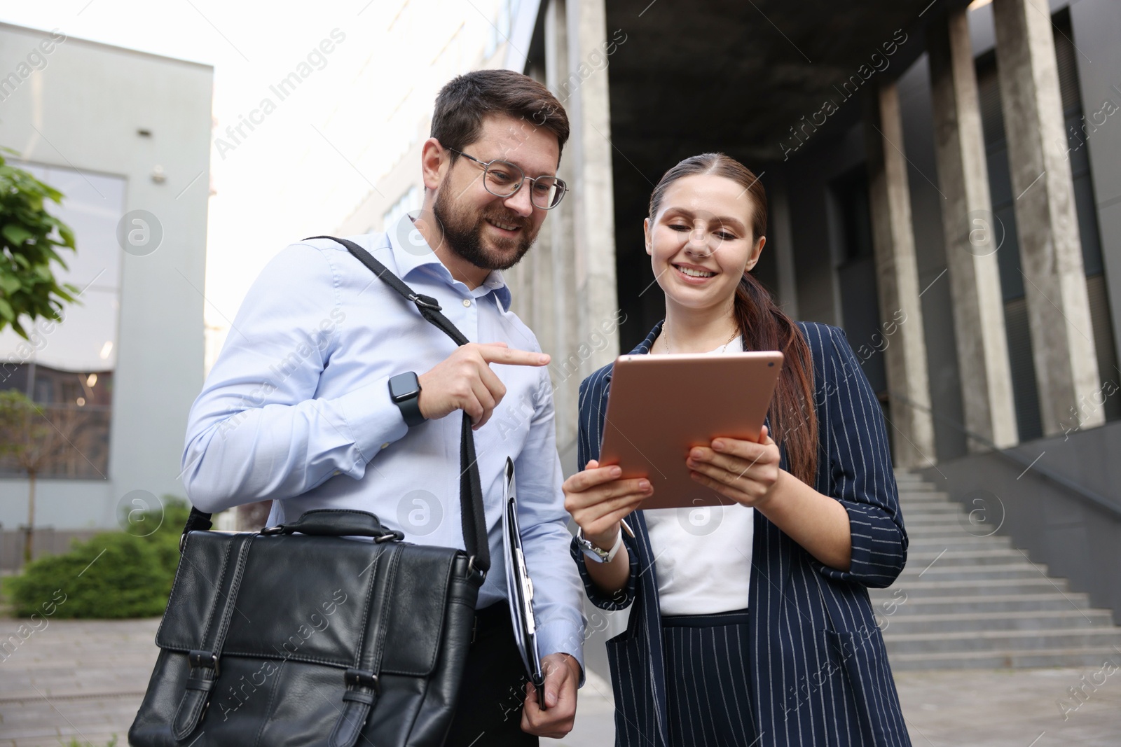 Photo of Happy coworkers with tablet near office building