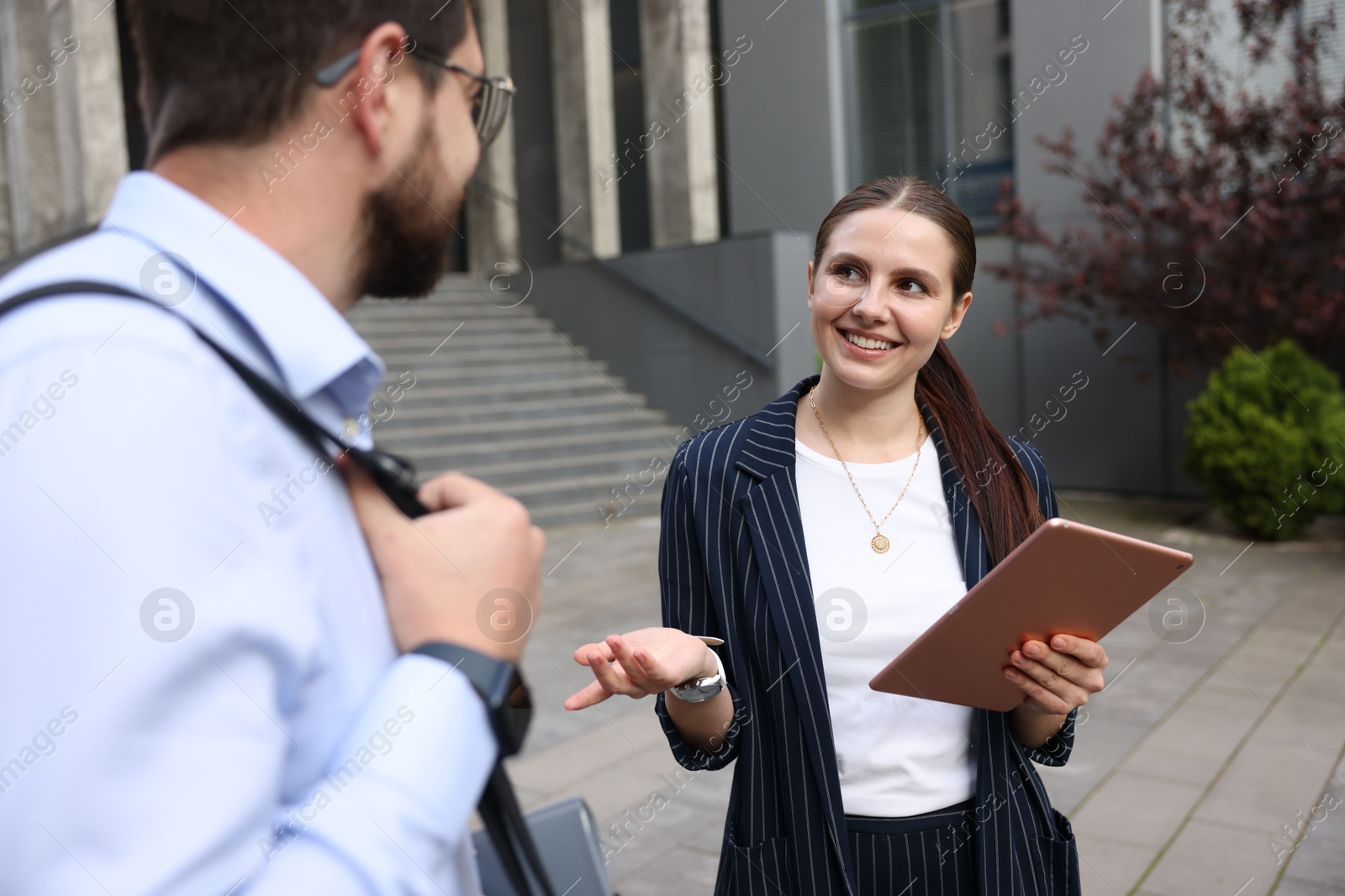 Photo of Happy coworkers with tablet near office building