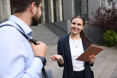 Photo of Happy coworkers with tablet near office building