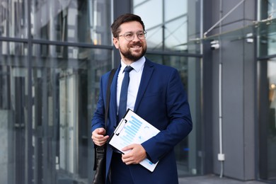 Photo of Successful businessman with clipboard near office building