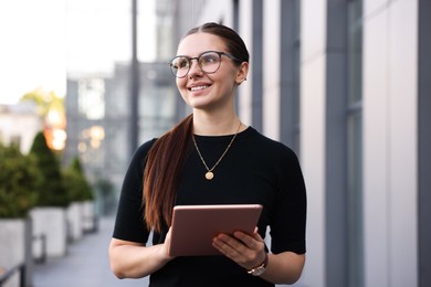 Photo of Successful businesswoman with tablet near office building