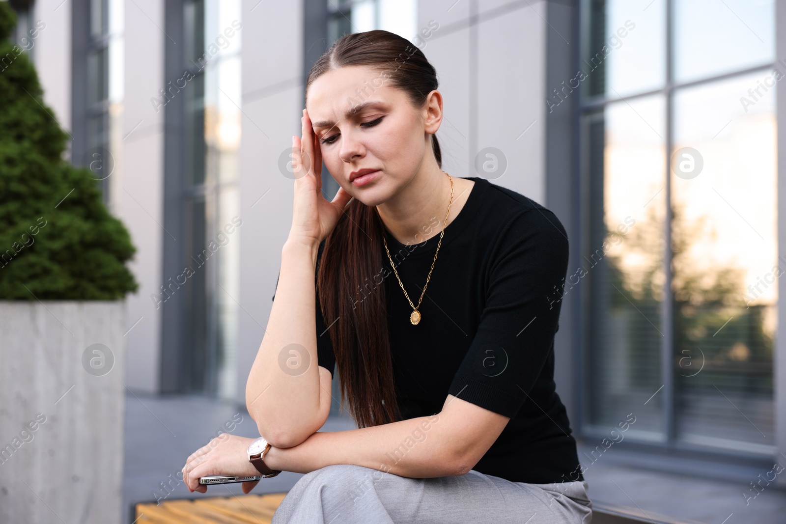 Photo of Tired businesswoman on bench outside office building