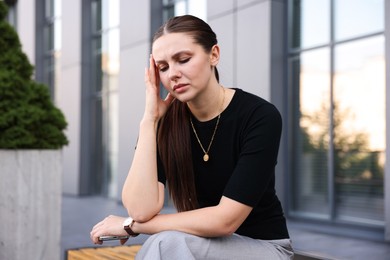 Photo of Tired businesswoman on bench outside office building