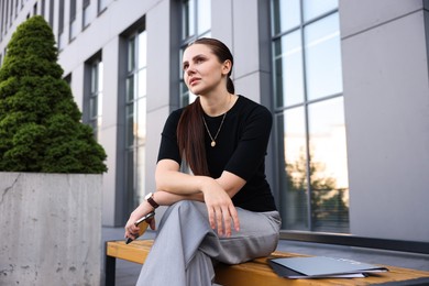 Photo of Tired businesswoman on bench outside office building