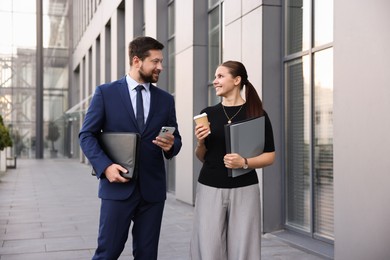 Photo of Happy coworkers discussing something near office building